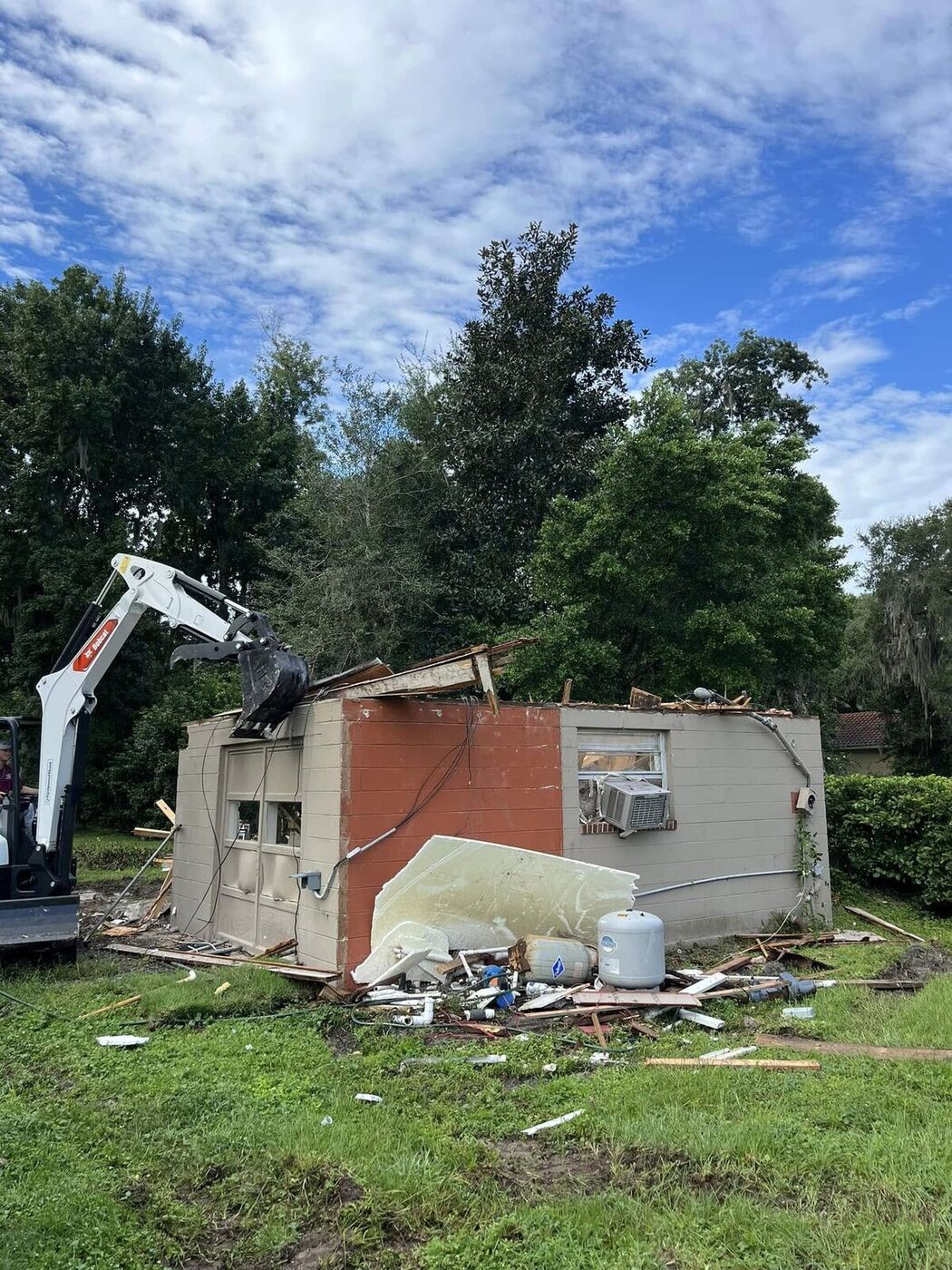 Bobcat excavator demolishing a small CBS structure during a residential tear-out job