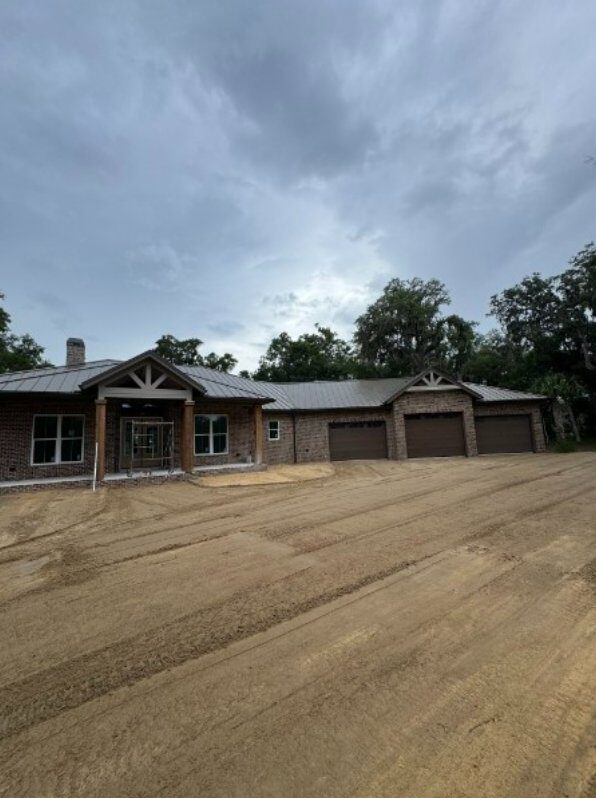 Finished custom brick home with completed site prep, grading, and driveway work